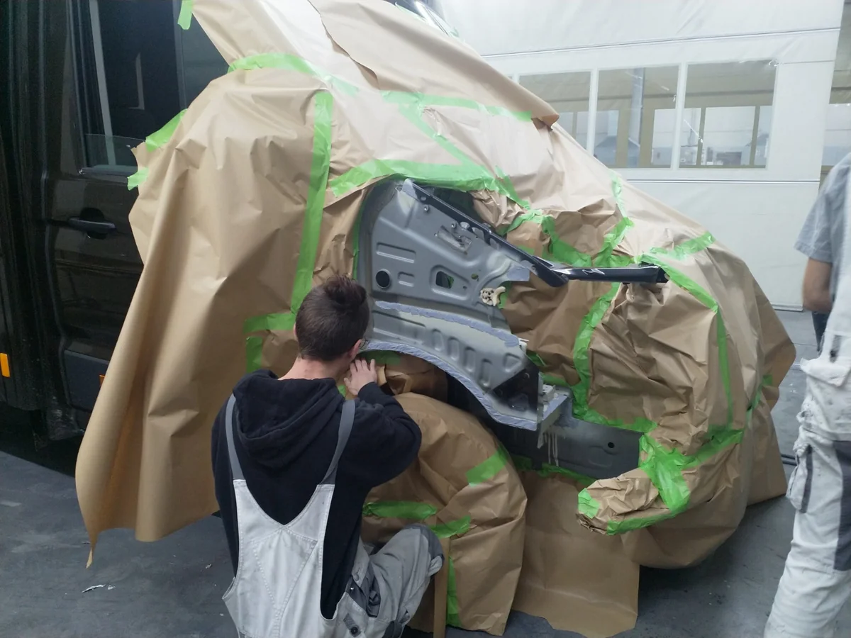 Mitarbeiter klebt Fahrzeug vor Lackierung ab — MV Lack & Karosserie